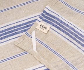 Blue and white linen dish towels draped beside fresh bread and kitchenware