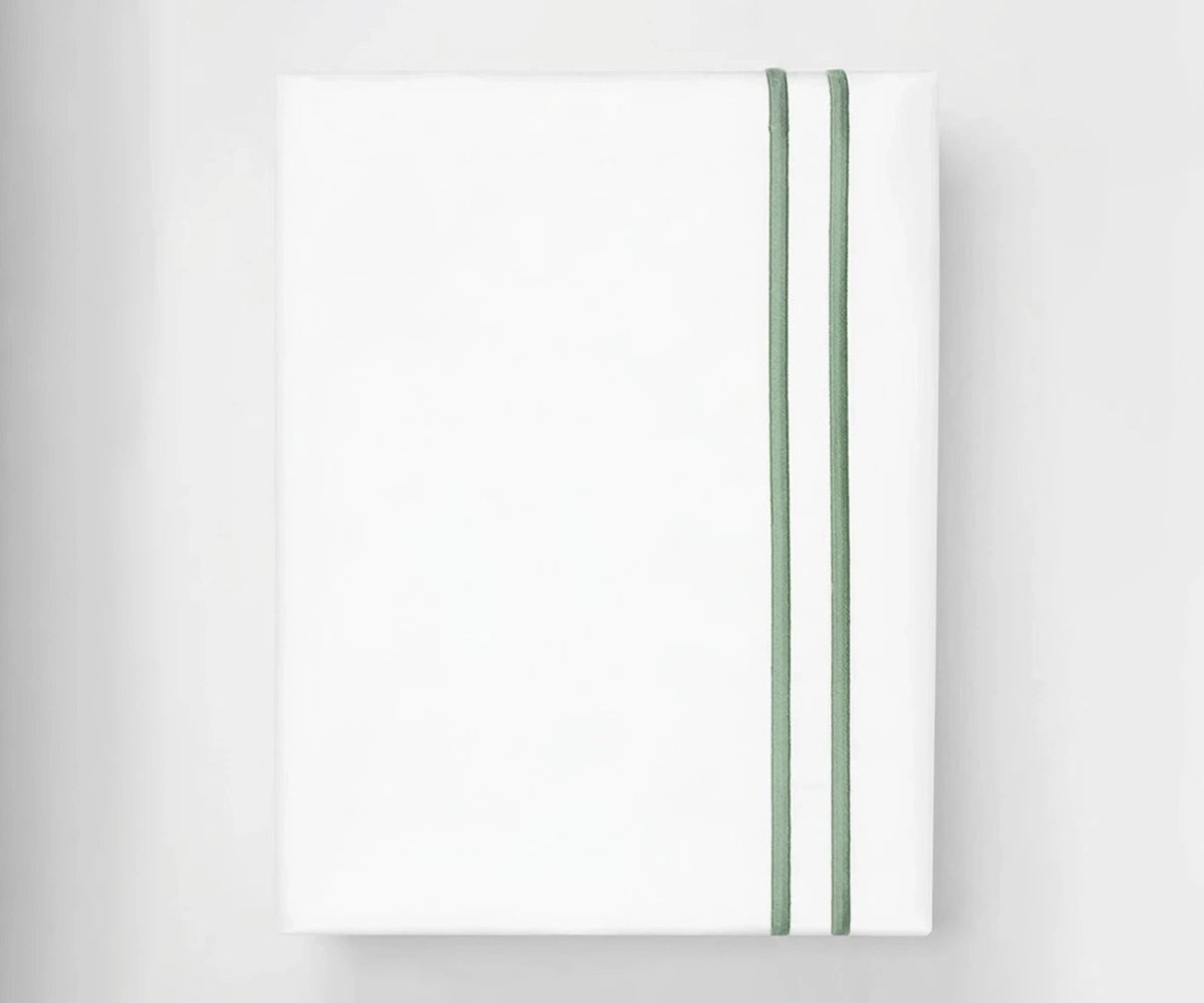 Neatly folded white cotton flat sheet featuring a decorative sage green double-line embroidered border.