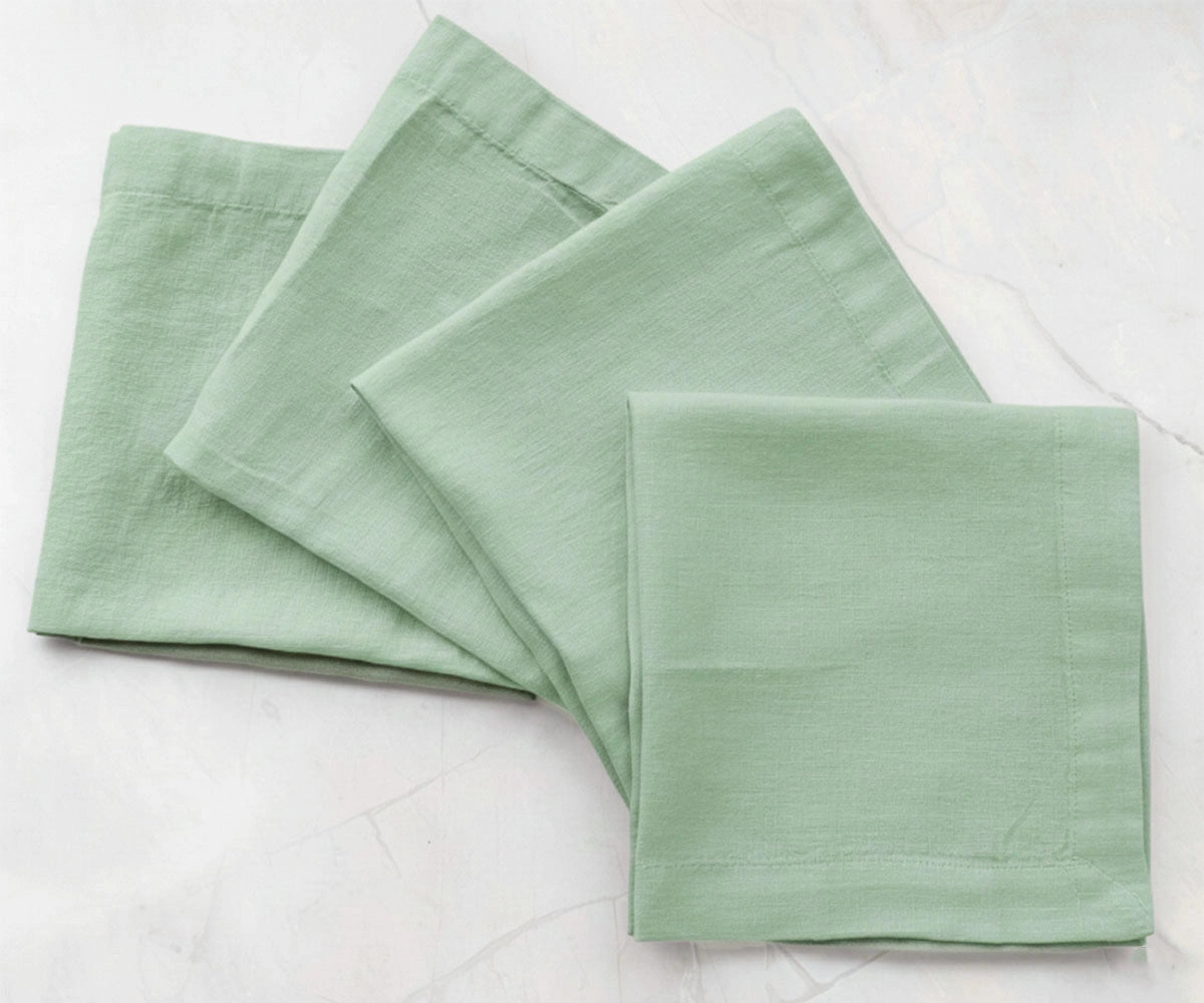 Sage green solid cotton linen napkins styled on dining table, reusable fabric napkins for natural table settings