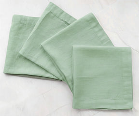 Sage green solid cotton linen napkins styled on dining table, reusable fabric napkins for natural table settings