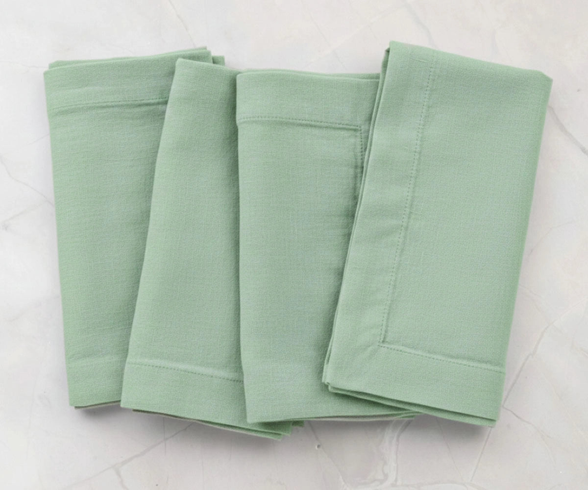 Folded sage green cotton linen napkins with plain solid finish, reusable dinner napkins for everyday dining