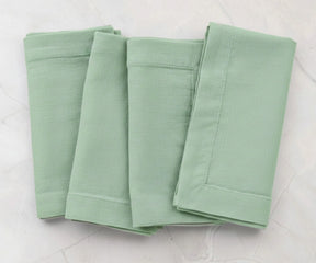 Folded sage green cotton linen napkins with plain solid finish, reusable dinner napkins for everyday dining