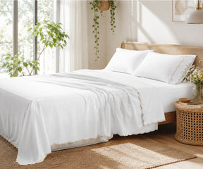 White bed sheet set with beige scalloped embroidery on the pillowcases and flat sheet.
