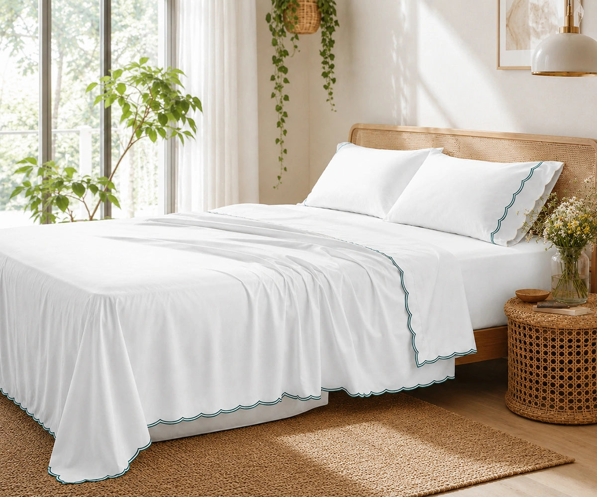 White bed sheet set with sage green scalloped embroidery on the pillowcases and flat sheet.