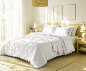 White bed sheet set with navy blue scalloped embroidery on a neatly made bed.