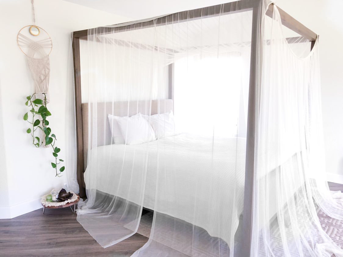 Canopy bed dressed in a white cotton fitted sheet with a matching canopy