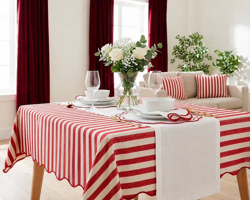 Dining room with a red and white striped tablecloth, white flowers, and a beige sofa.