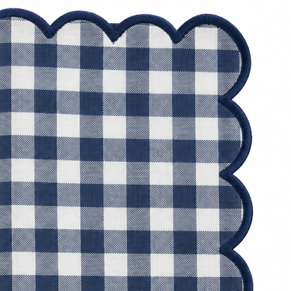 Close-up of navy blue and cream gingham cotton dinner napkin with matching red scalloped embroidered edge