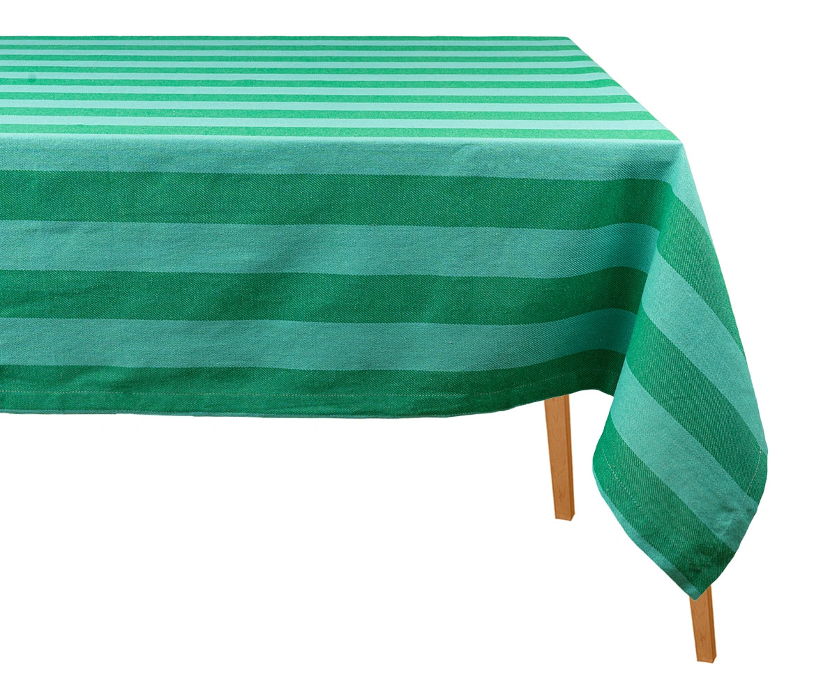 Green striped cotton tablecloth draped over a wooden dining table against a plain white background.