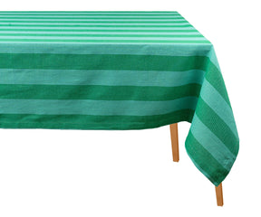 Green striped cotton tablecloth draped over a wooden dining table against a plain white background.