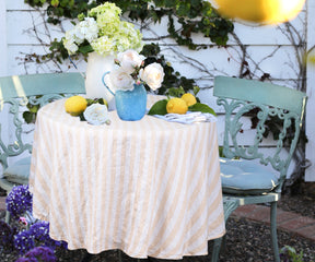 Outdoor table with striped linen tablecloth, fresh lemons, and floral decor.