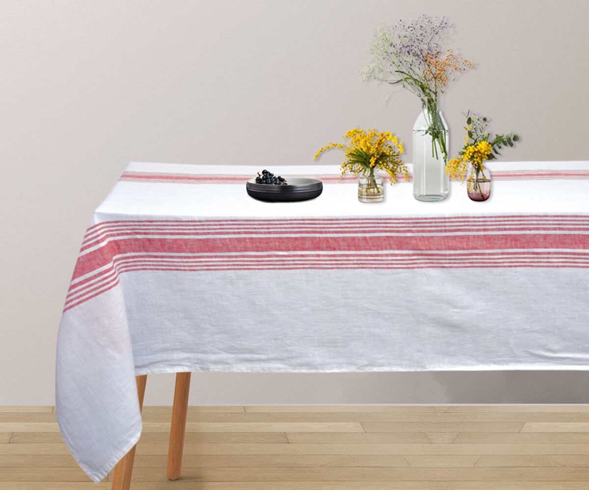 Red  linen tablecloth on a table with a vase of fresh flowers as a centerpiece.