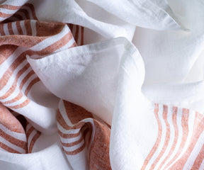 Detailed view of a white linen tablecloth with red stripe accents