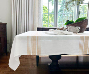 White linen-covered dining table with a rustic brown vase as decor