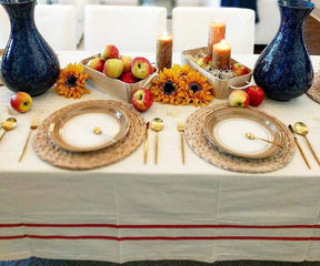 Thanksgiving table setting on a French tablecloth with apples, sunflowers, and gold plates