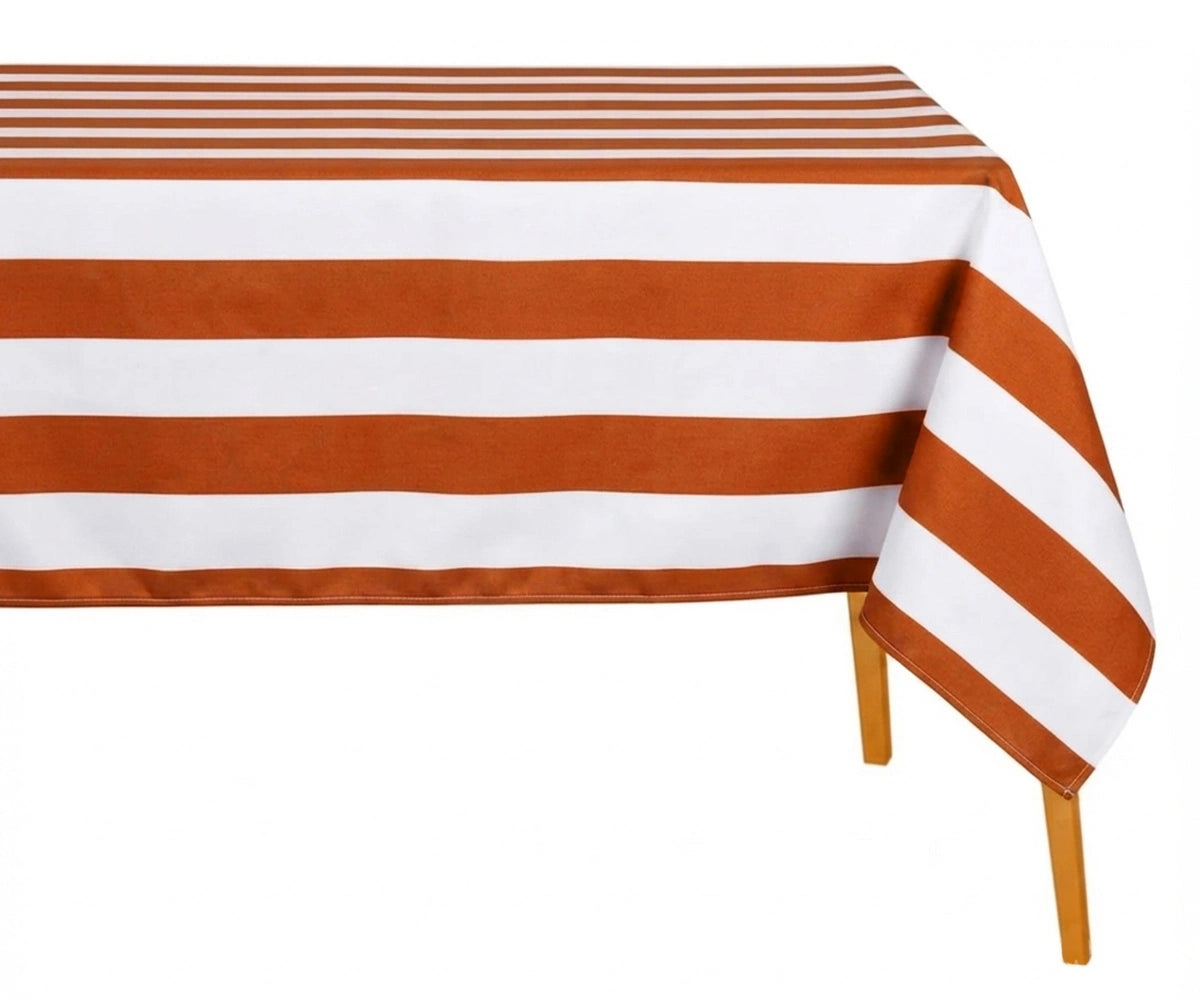 terracotta and white wide cabana striped cotton linen tablecloth with straight edges draped over a dining table.