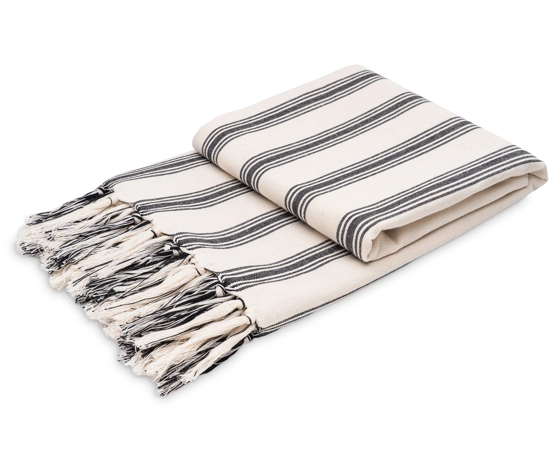 Black and white striped cotton throw blanket with tassel fringe styled on a sofa