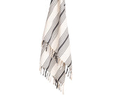 Black and white striped cotton throw blanket draped over a light‑gray sofa with neutral cushions

