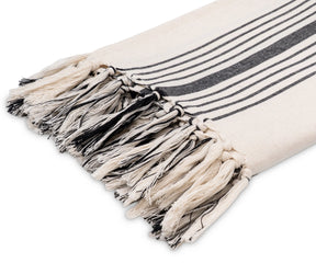 Lightweight black and white cotton throw with fringe detail, adding a cozy and modern accent to a living space