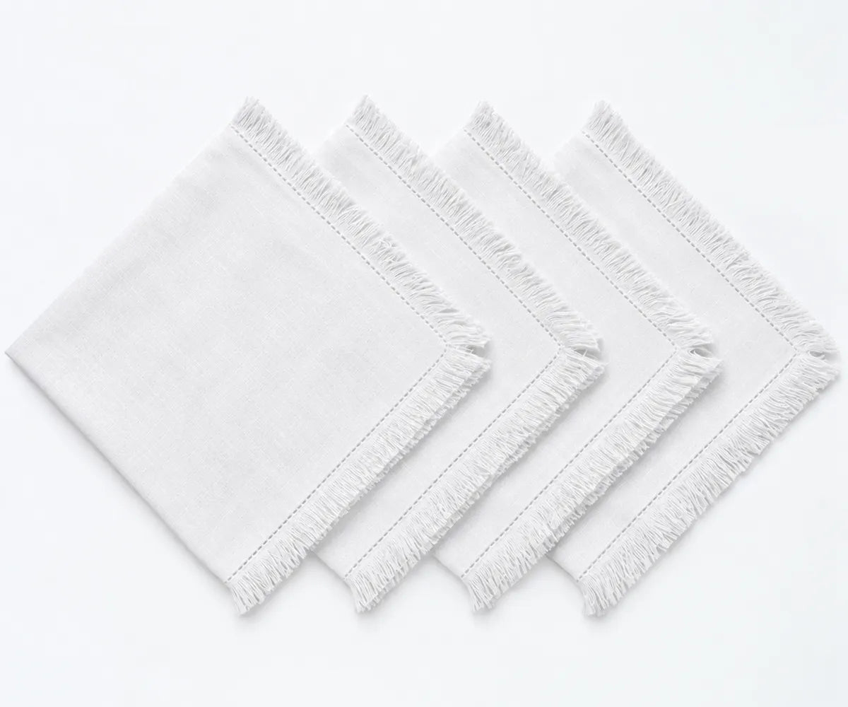 White cotton dinner napkin with a simple plain design and fringe edge detailing for everyday dining and table settings