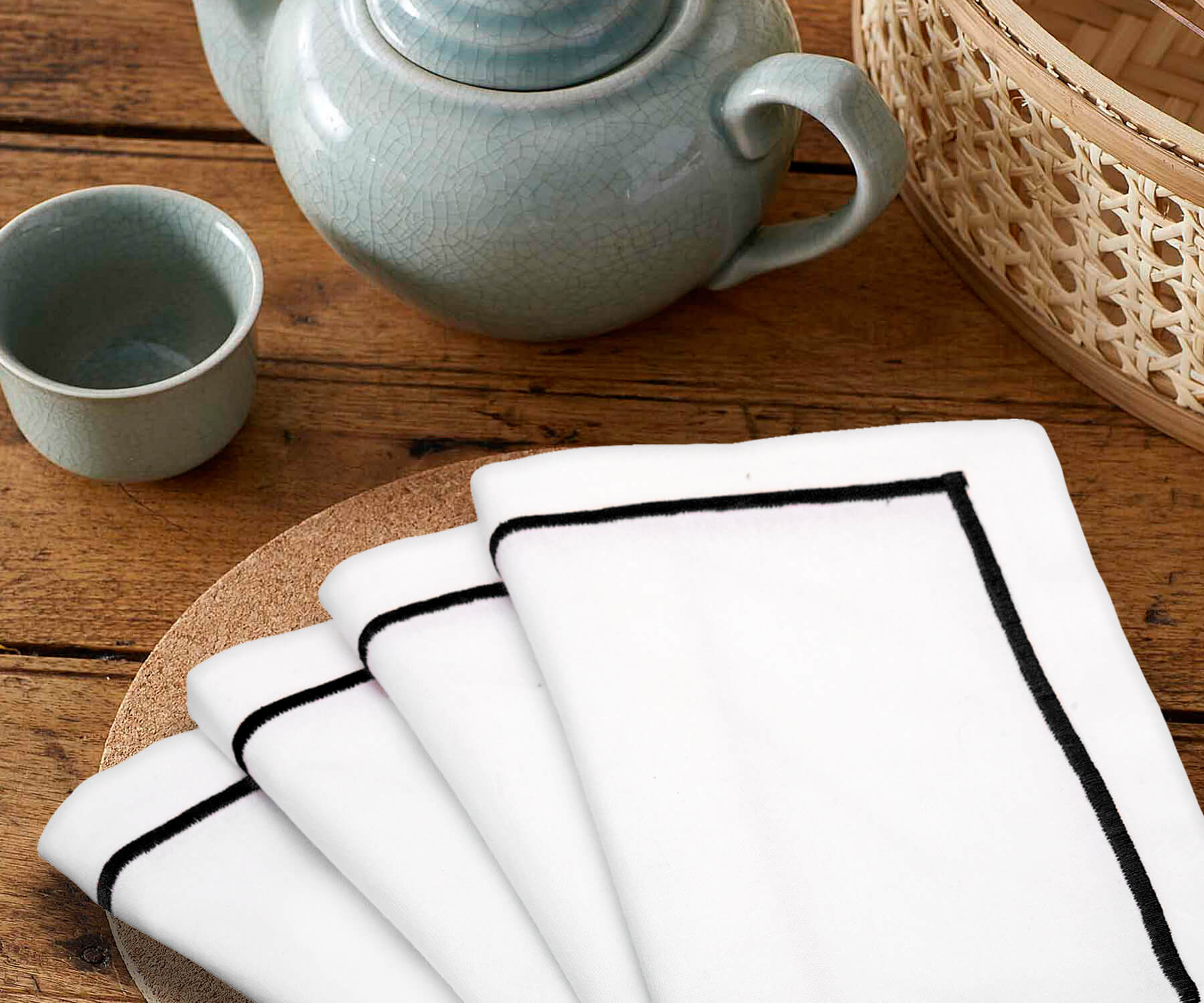 Single white dinner napkin with black trim on a wooden table