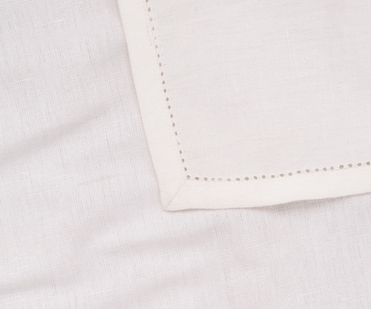 White hemstitched dinner napkin styled on a formal table setting