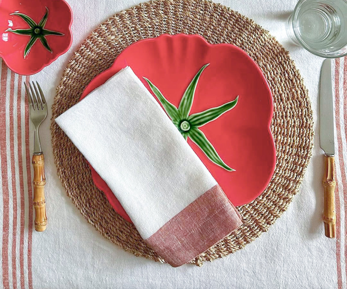 Stack of folded red linen napkins on a white tablecloth