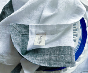 Several folded cloth napkins and linen cocktail napkins on a ceramic tray