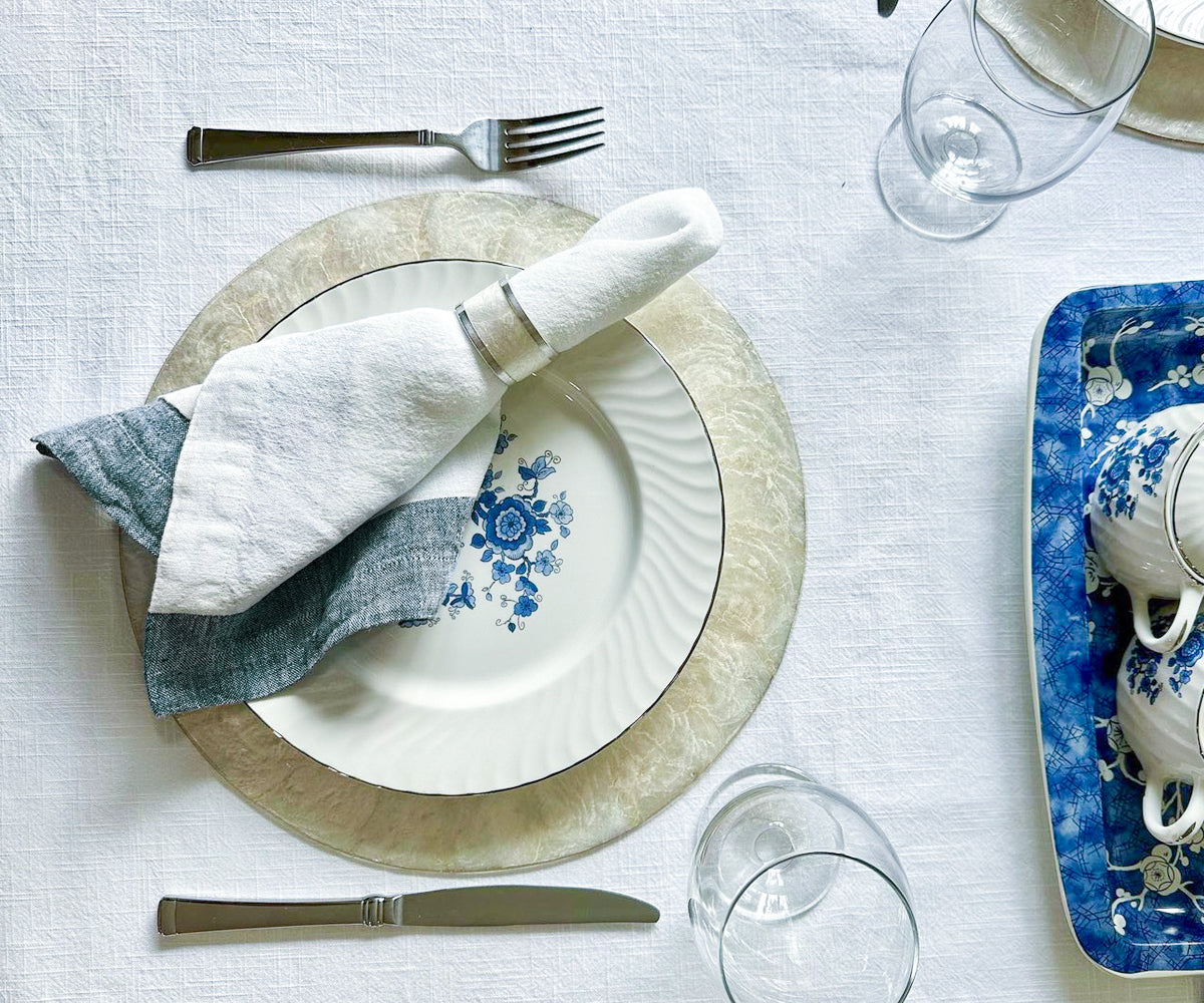 Table laid with dinnerware and green linen napkins in an outdoor setting