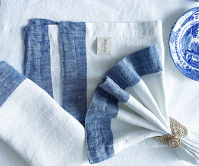 Stack of white and blue linen napkins on an antique wooden shelf