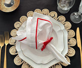 Set of white and red linen napkins displayed on a rustic dining table.