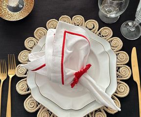 Set of white and red linen napkins displayed on a rustic dining table.