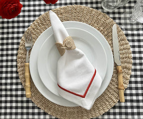 Place setting with a white dinner napkin, red accents and roses
