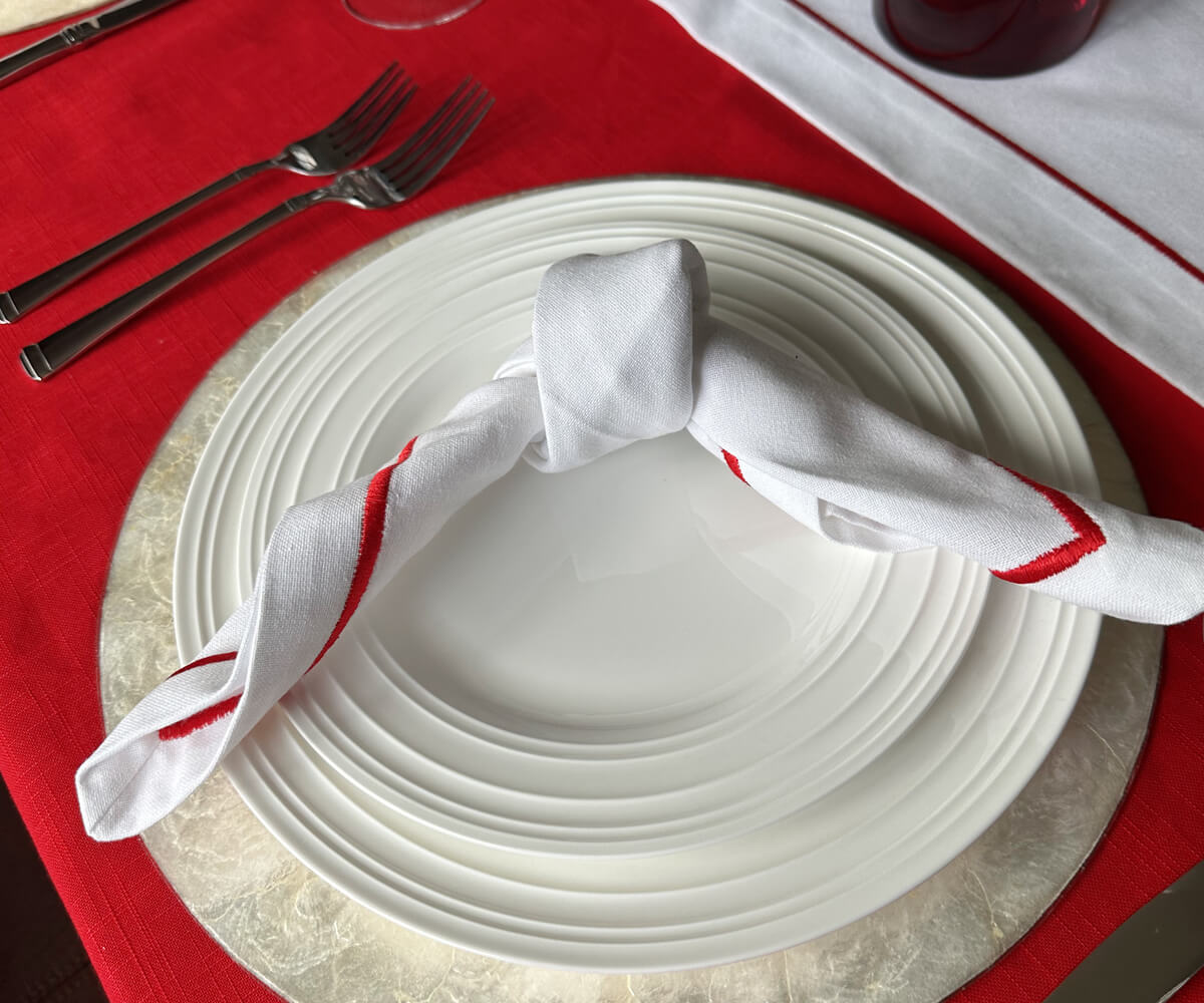 Table setting with red and white theme featuring white dinner napkins