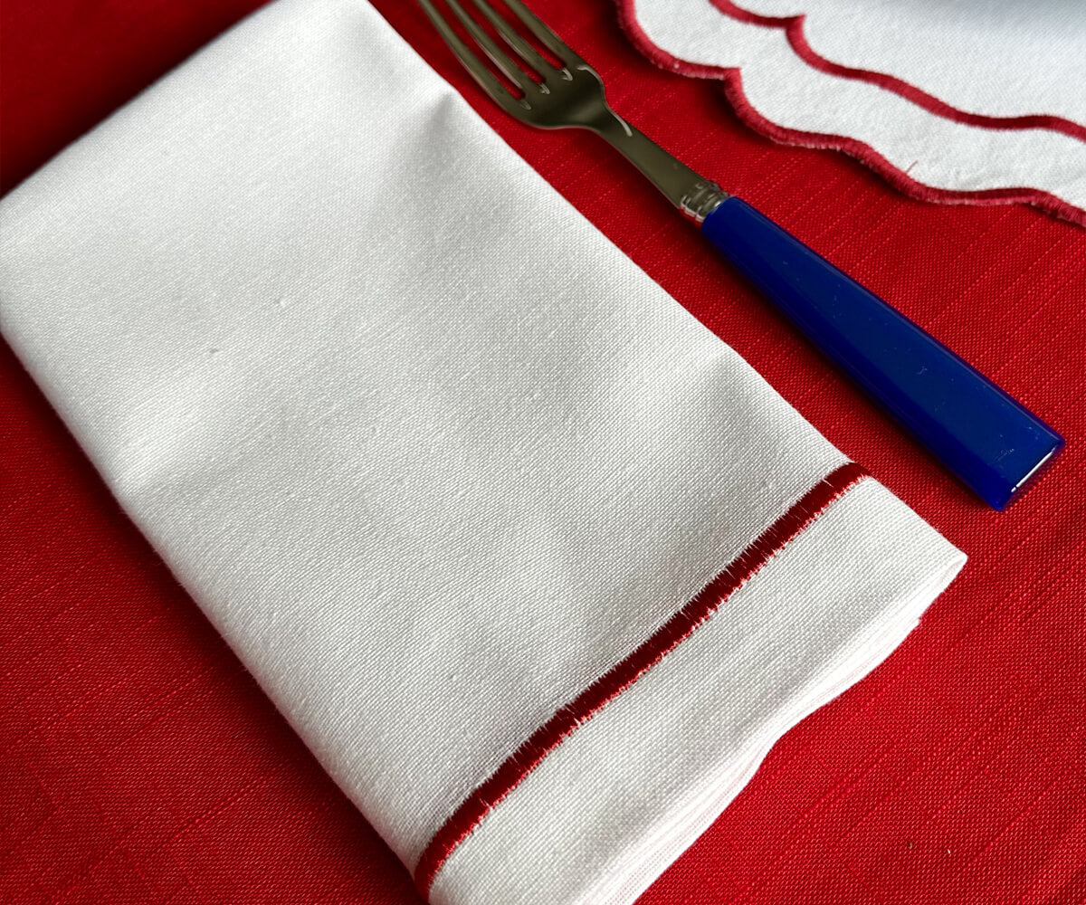 White dinner napkin and fork on a red tablecloth