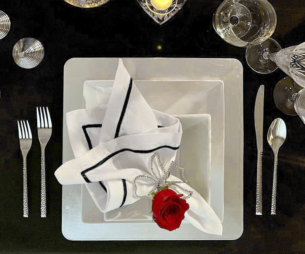 Black cloth napkin presented on a white square dinner plate
