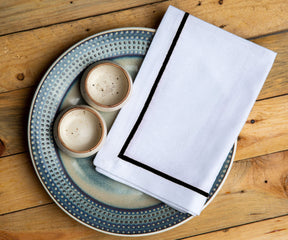 White dinner napkin displayed with two cups on a plate