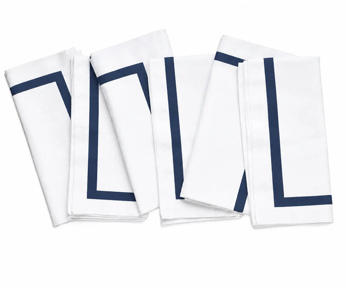 White cotton dinner napkins featuring a neatly finished decorative border, adding a polished touch to the dining table.