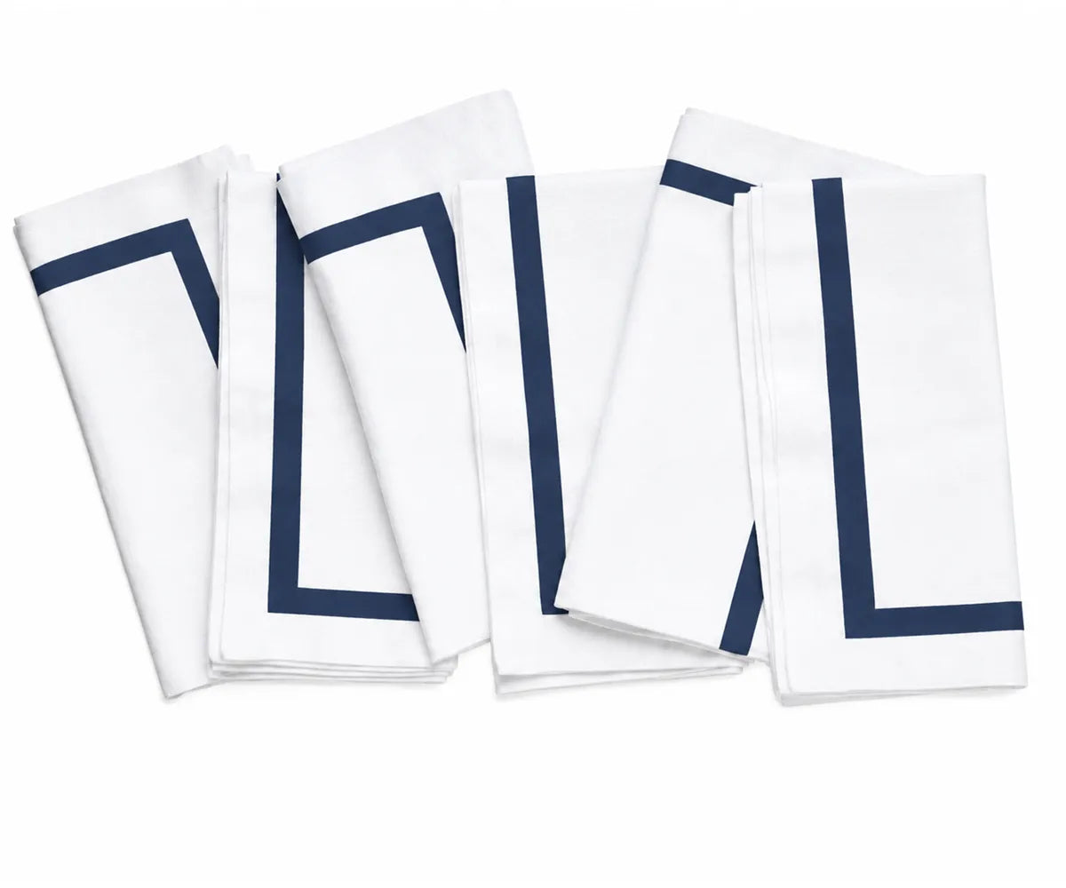 White cotton dinner napkins featuring a neatly finished decorative border, adding a polished touch to the dining table.