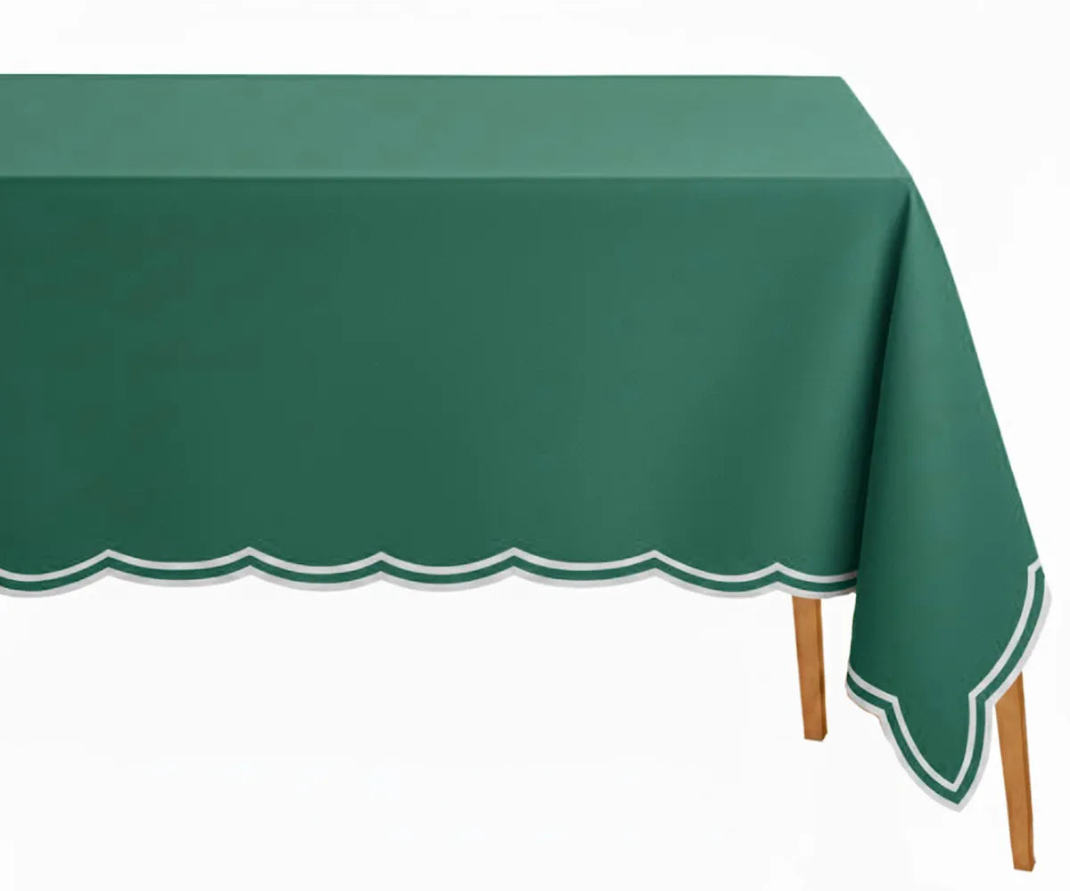 Green embroidered rectangle tablecloth with white scalloped edge on dining table