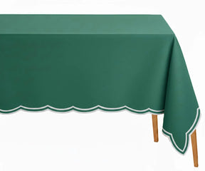 Green embroidered rectangle tablecloth with white scalloped edge on dining table
