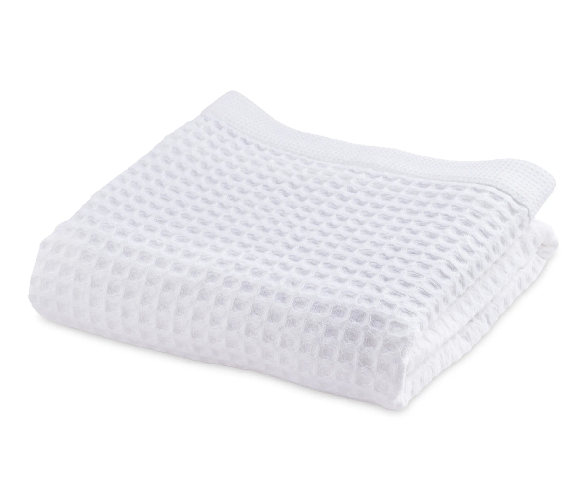 A high-resolution image showing a neatly folded white cotton waffle towel with a textured waffle weave pattern, highlighting its softness, absorbency, and thick quality. Ideal for home, spa, or gym use.