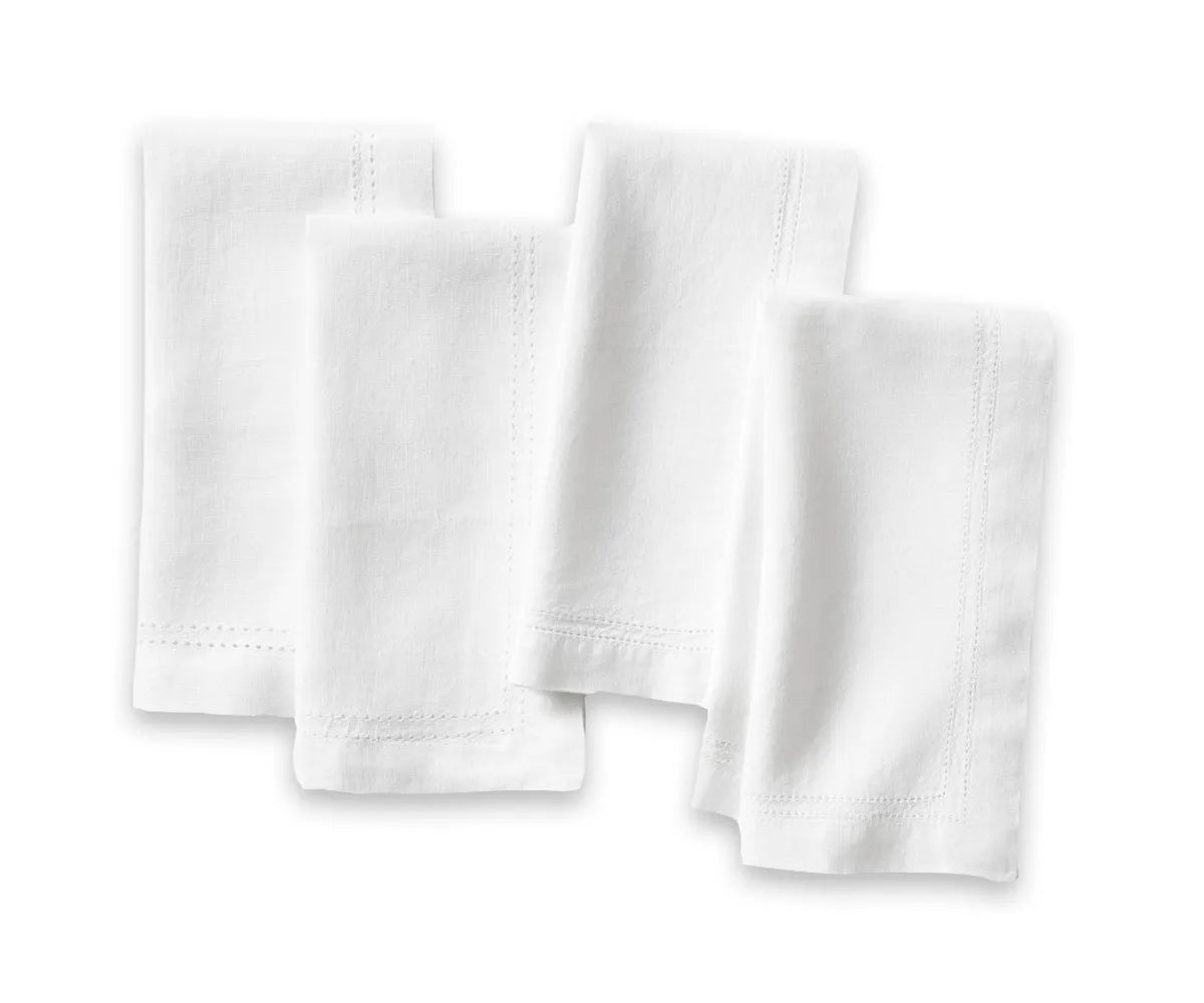 Elegant white linen hemstitch napkins neatly folded on a dinner table setting