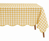 A rectangular table covered with a yellow and white gingham checkered tablecloth featuring a scalloped edge and draped over the sides, shown on a plain white background.