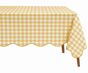 A rectangular table covered with a yellow and white gingham checkered tablecloth featuring a scalloped edge and draped over the sides, shown on a plain white background.