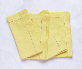Close-up of hemstitch detailing on butter yellow cloth napkin
