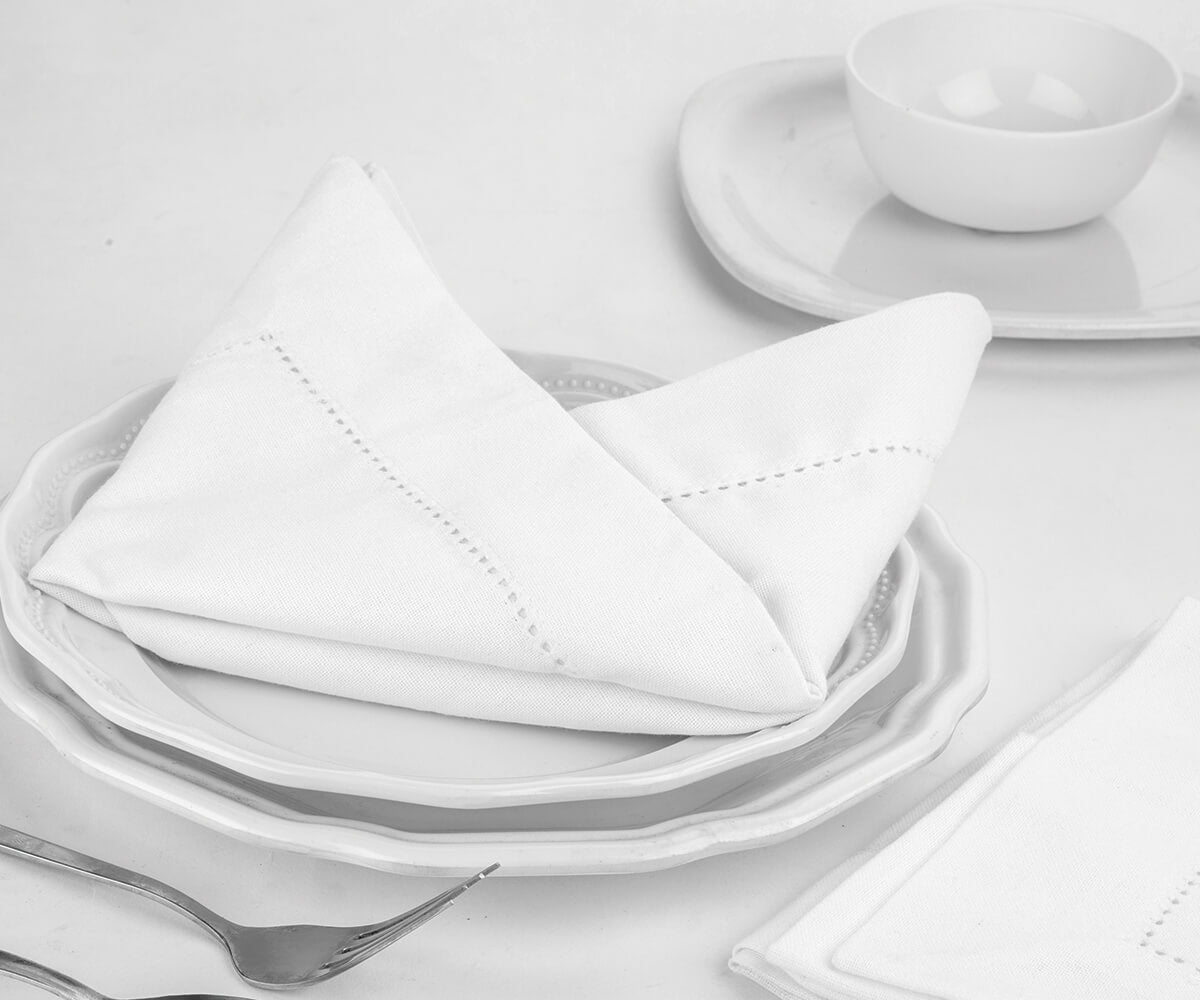 Folded cotton dinner napkins with 1" borders are placed on the plate as cloth napkins bulk