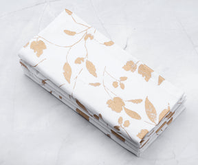 Set of 4 folded Printed napkins which are white cloth napkins - Metallic linen napkins are arranged in white background 