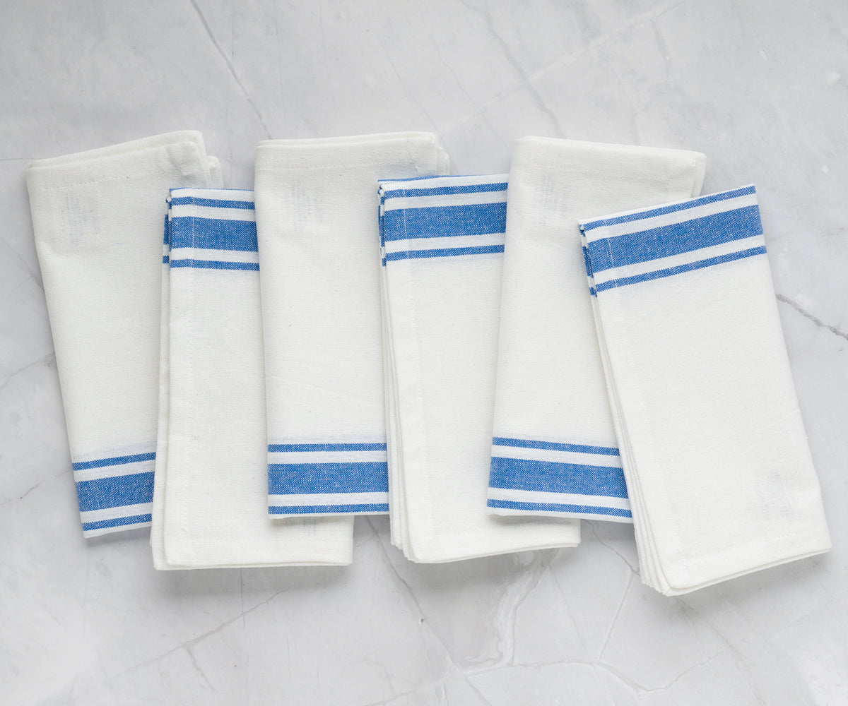 White and blue striped bistro napkins displayed on a marble countertop