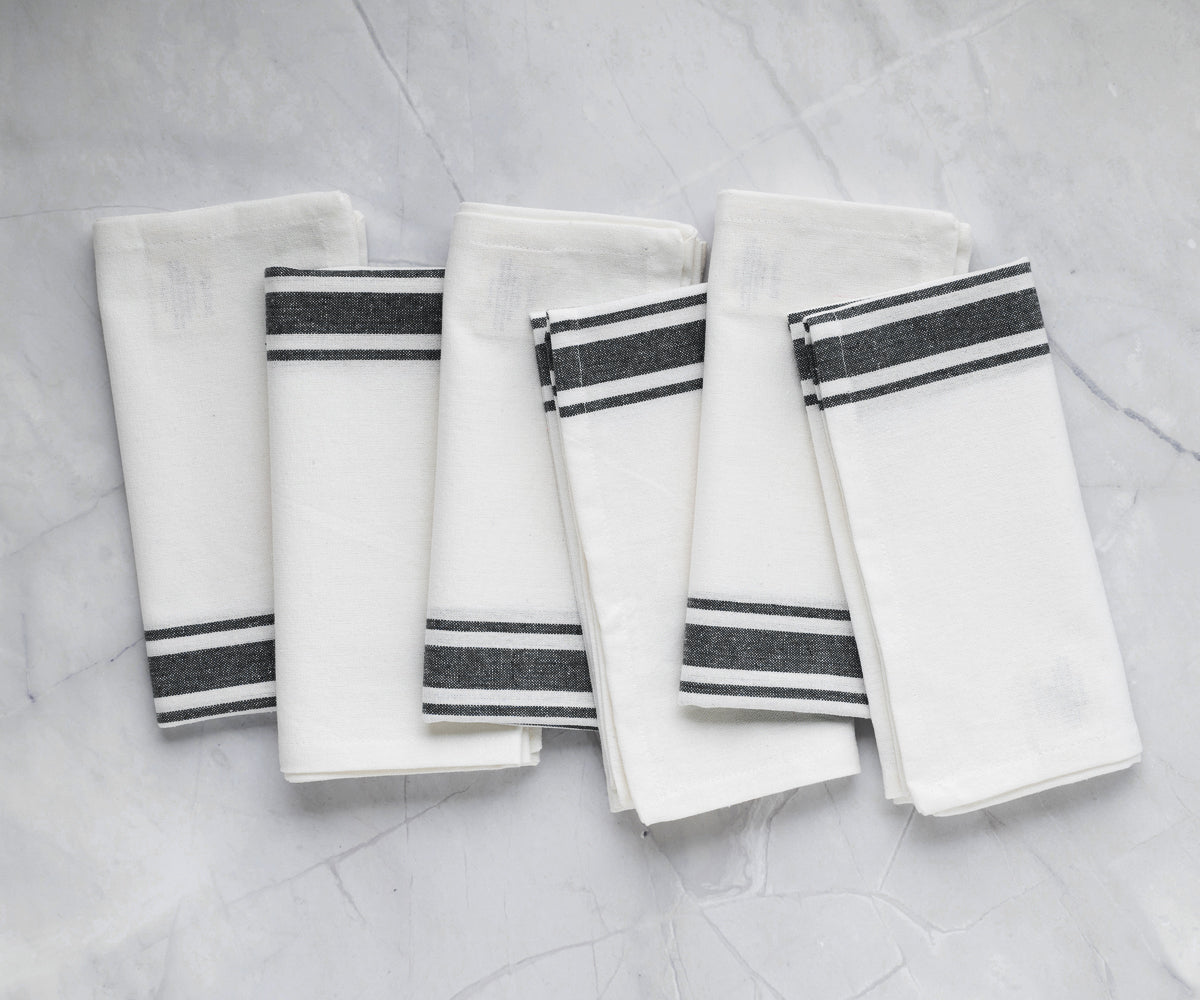 Four bistro napkins in white with blue stripes neatly arranged
